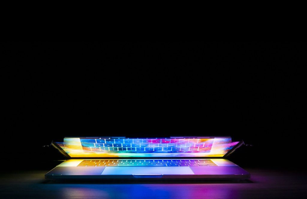 a laptop beginning to open, shining light out of it