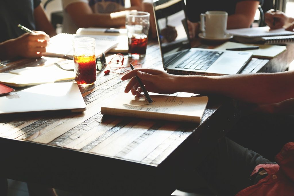 books, notes, and drinks on the desk at an in person meeting